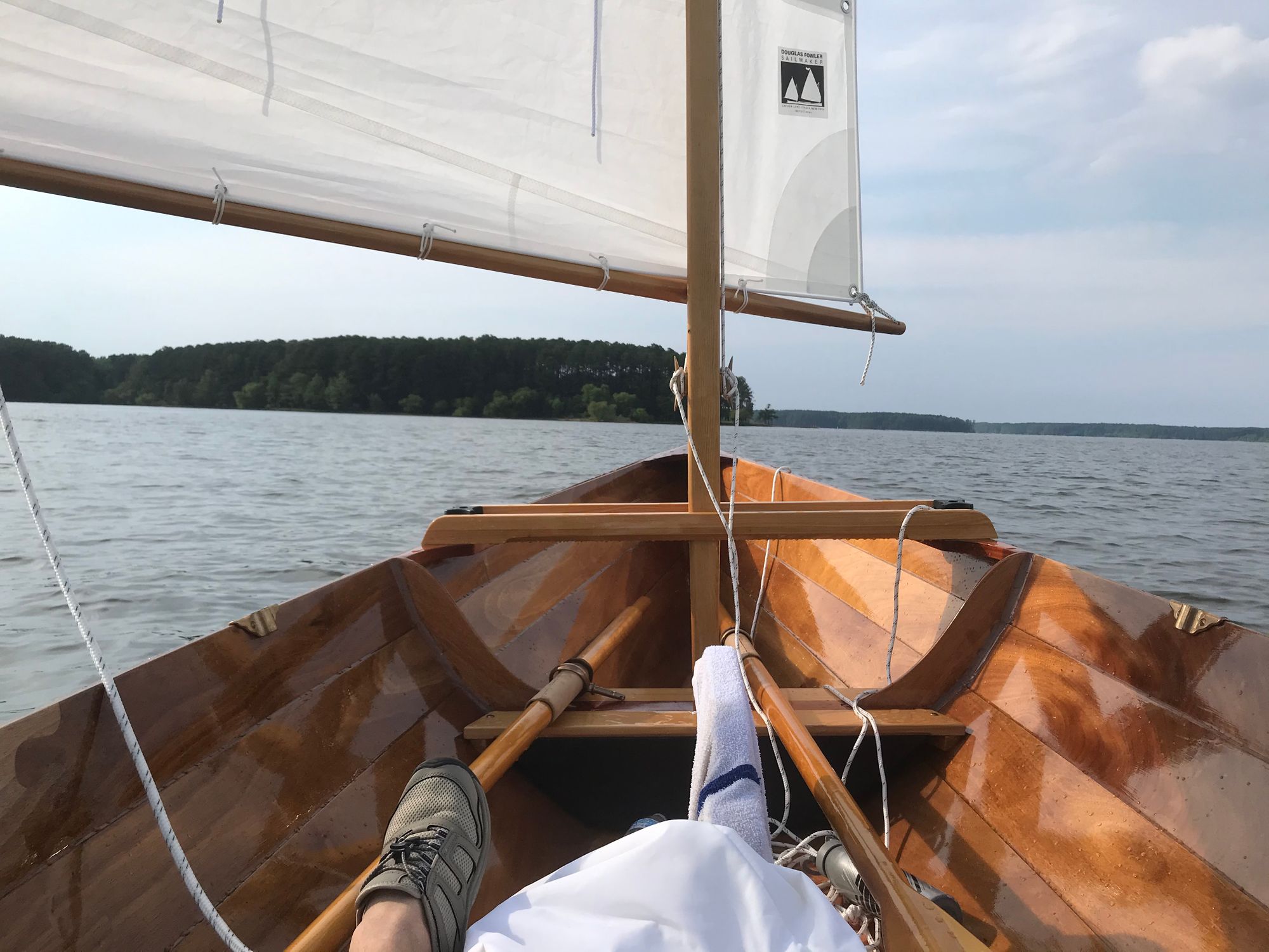 Picture of the bow of a sailboat, with sail, oars, and foot in view